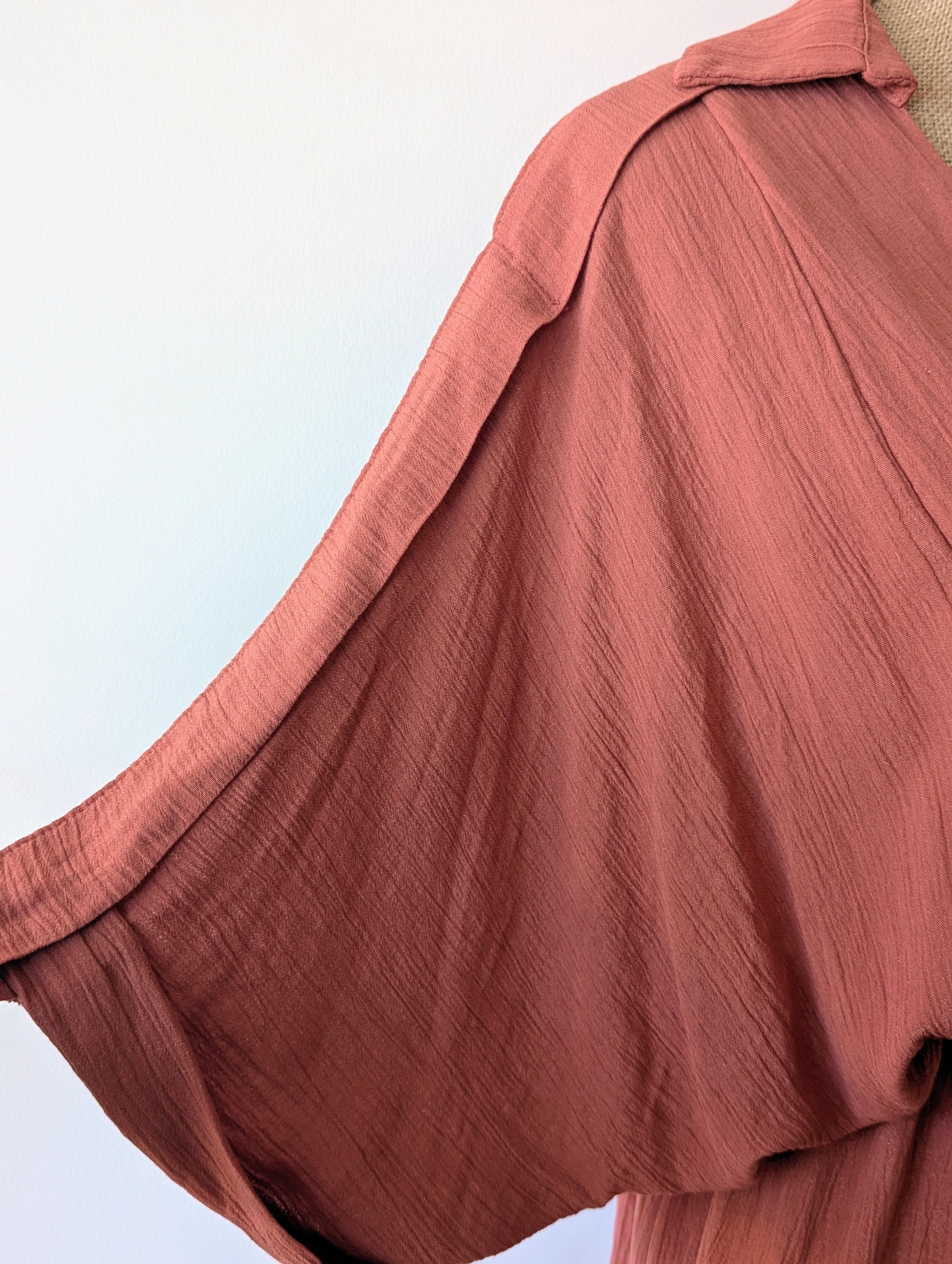 Robe longue terracotta en viscose avec fil dore.  Col chemise et drapé sur le devant. Manches chauves souris.